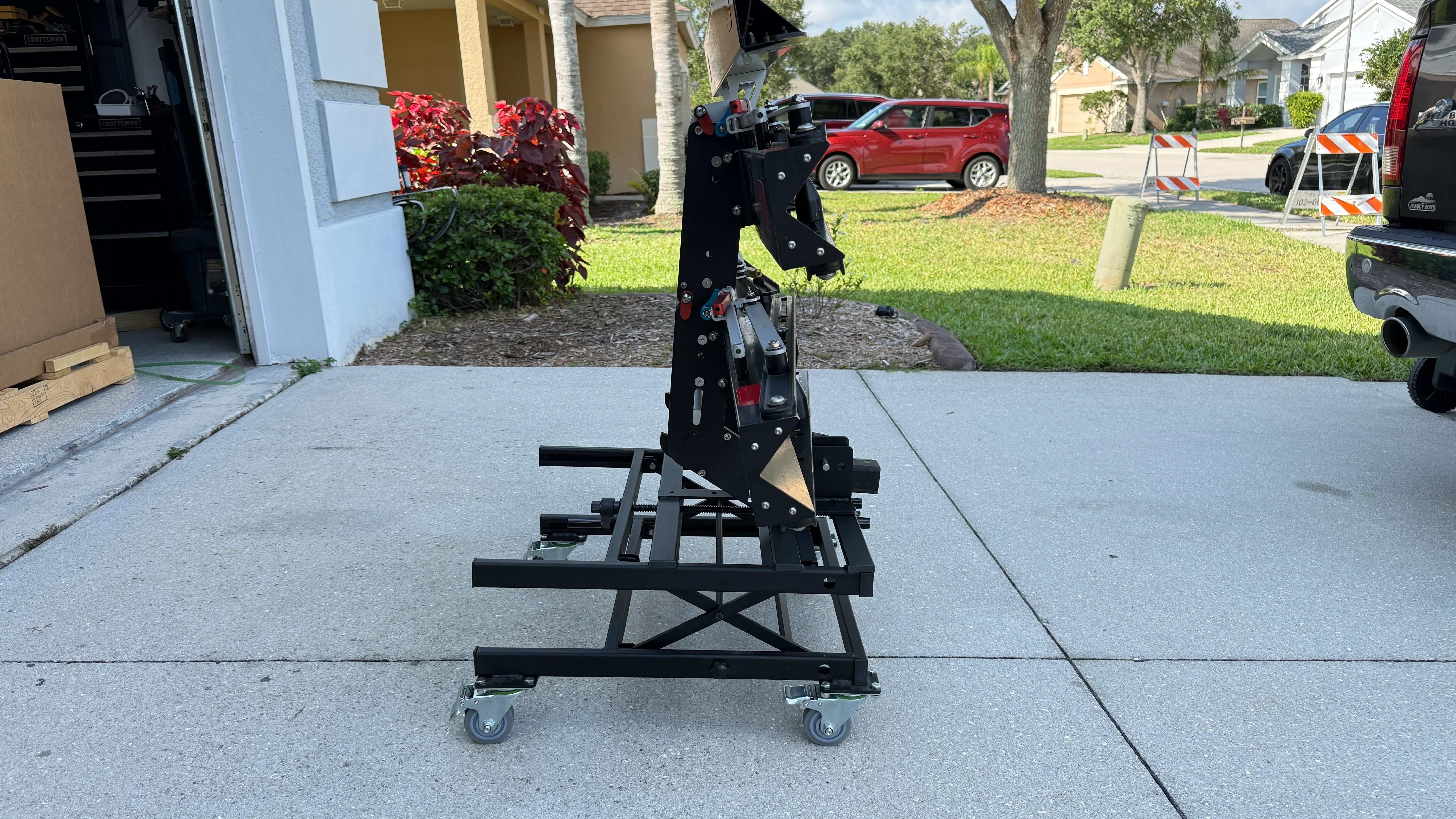 Black eBike Rack Lift on caster wheels outside a garage for easy lifting and aligning of heavy bike racks.