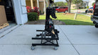 Black eBike Rack Lift on caster wheels outside a garage for easy lifting and aligning of heavy bike racks.