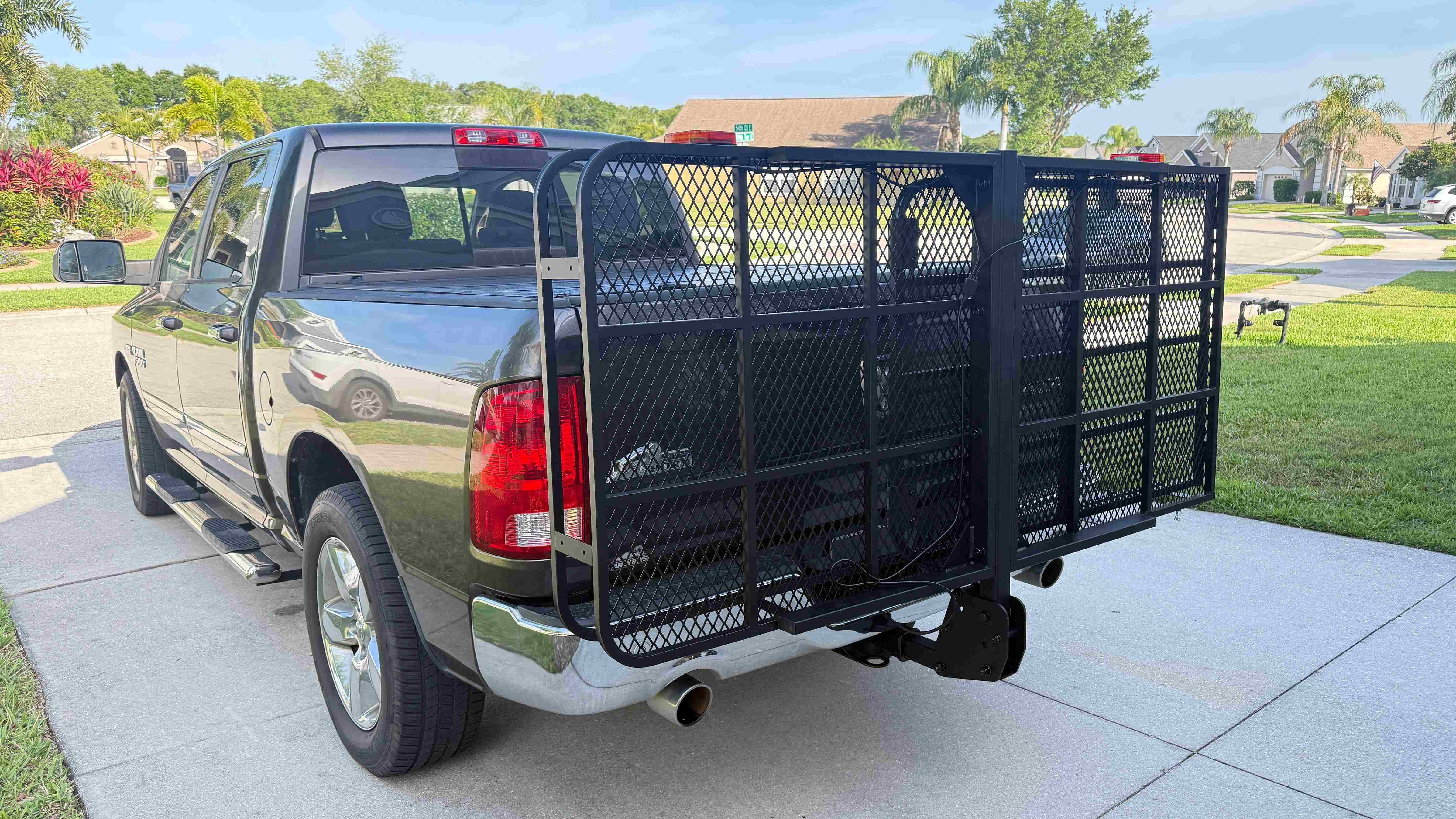 Black steel hitch mount cargo carrier with folding ramp attached to a pickup truck