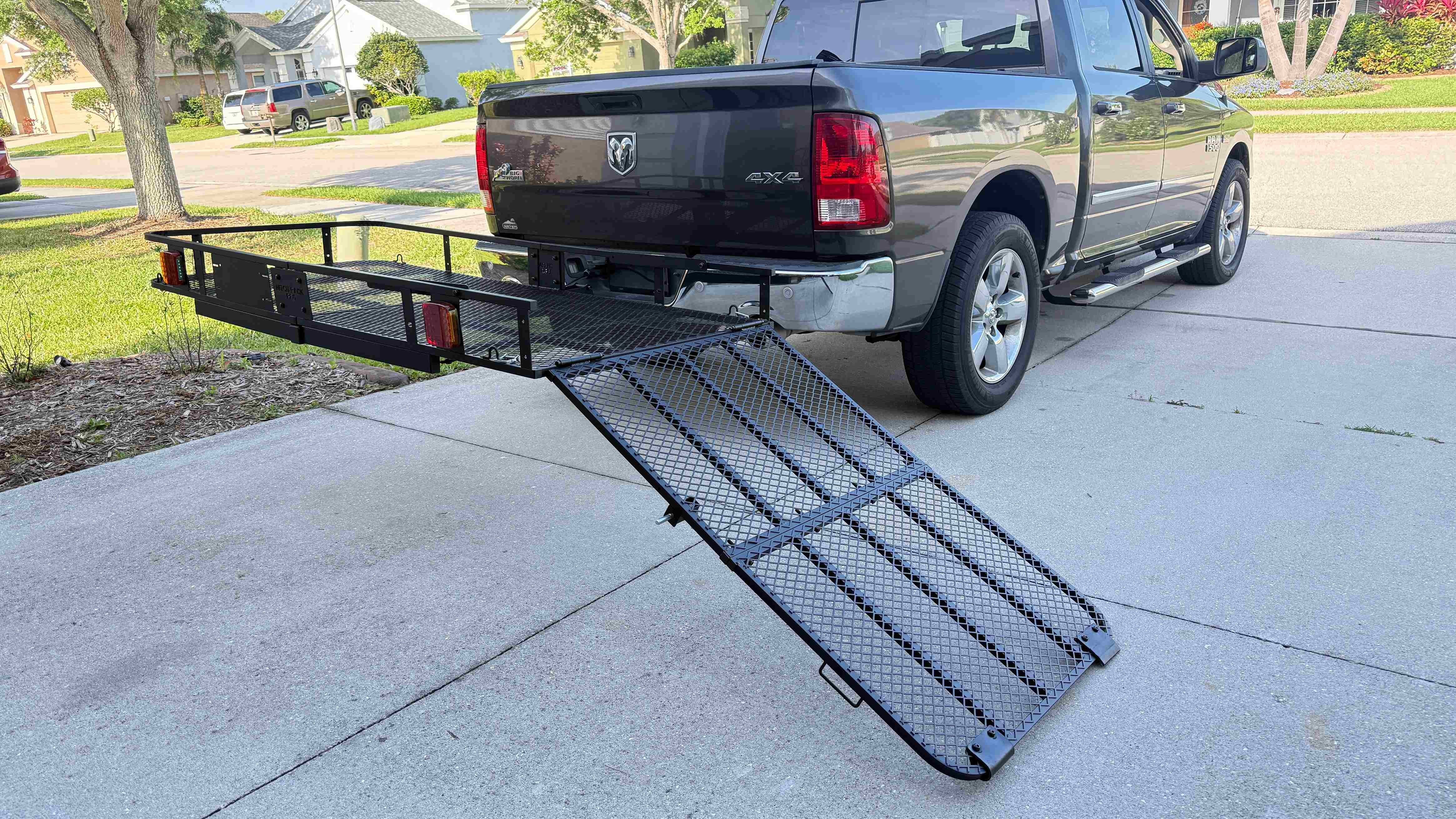 Hitch-mounted mesh cargo basket with a long folding loading ramp extended to the ground
