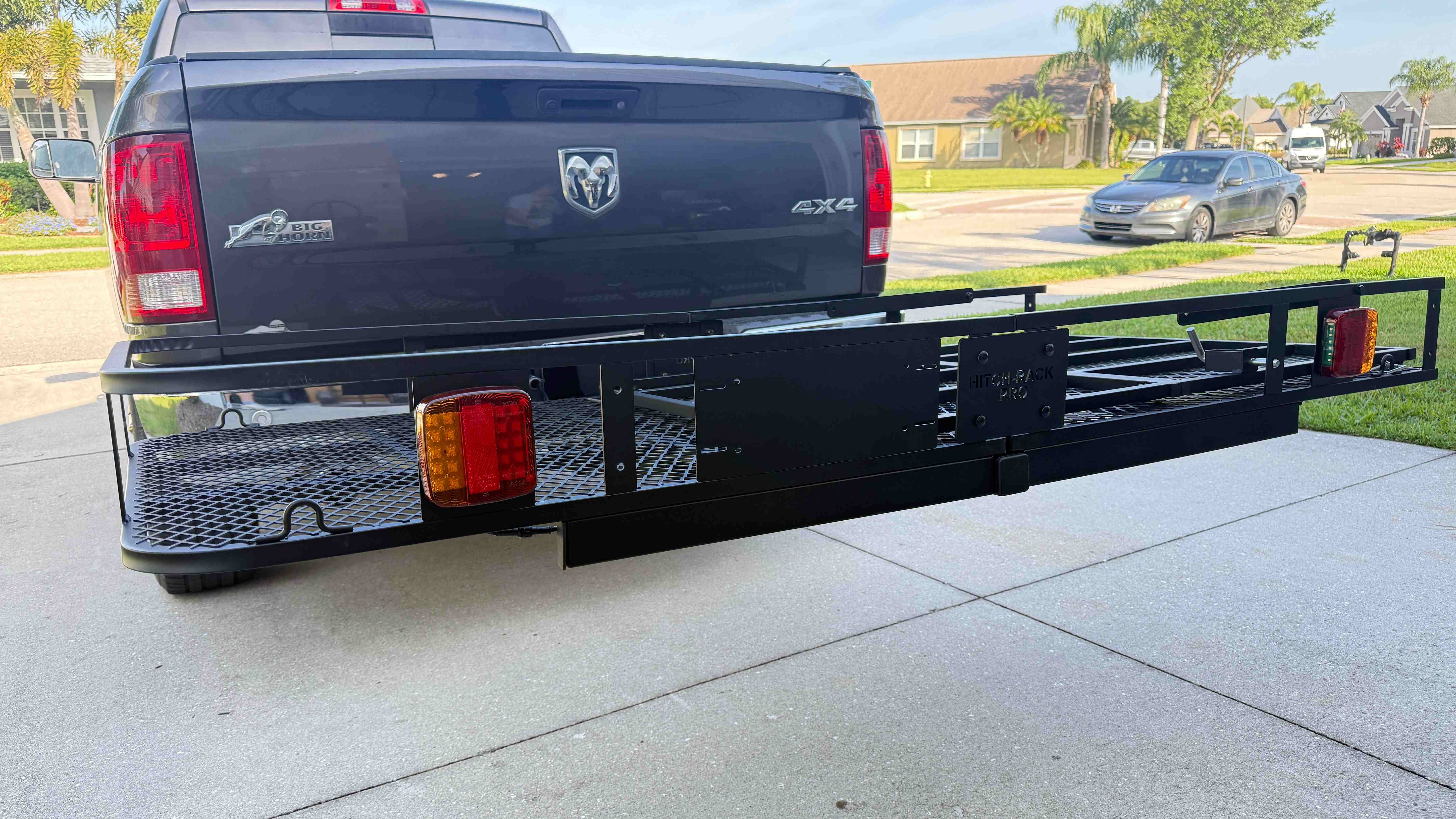 Hitch Rack Pro heavy-duty steel cargo carrier with folding ramp and integrated taillights mounted on a pickup truck